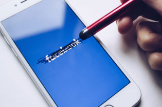 Hand using a stylus to cross out the word "facebook"
